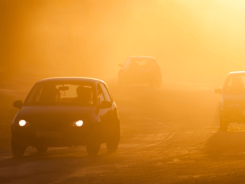 Hazy view of cars on a road due to a wildfire